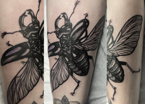 a black and white ink tattoo of a stag beetle flying