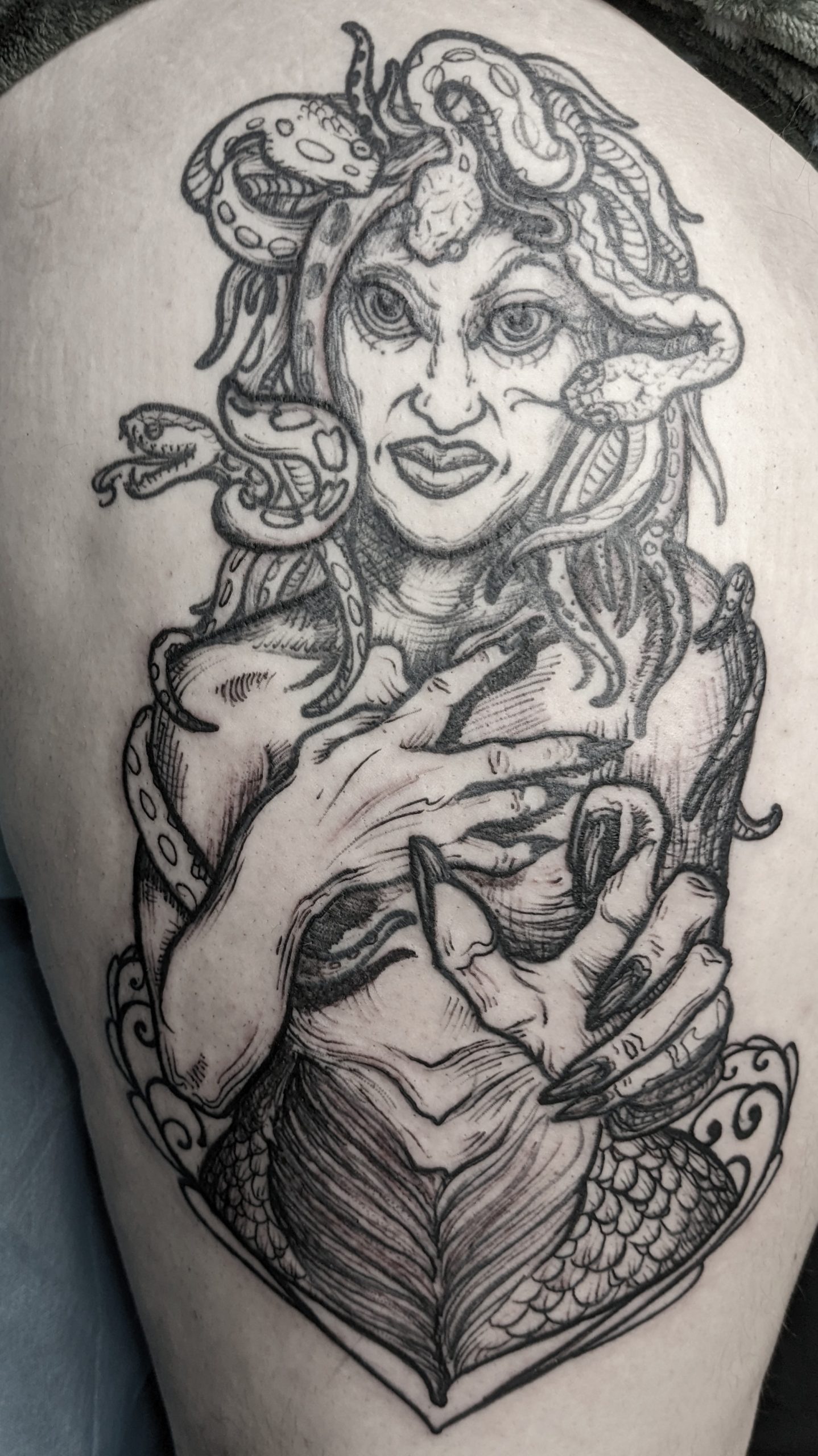 a tattoo that looks like an engraving of a non sexual Medusa reaching out her hand with an angry smile